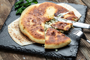 pie with cheese, potatoes, herbs, cottage cheese. National Caucasian dish on wooden background, top view