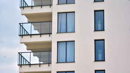 Modern white facade of a residential building with large windows. View of modern designed concrete apartment building.