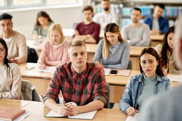 Large group of college students attending lecture in classroom.