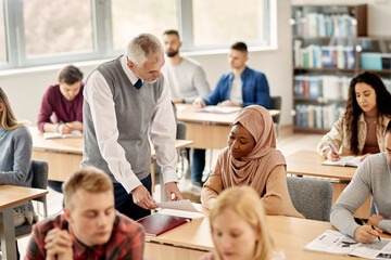 Senior professor talking to African American Muslim student during a class in the classroom.