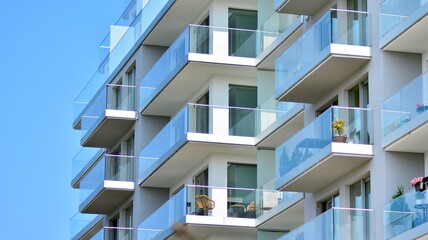 New apartment building with glass balconies. Modern architecture houses by the sea. Large glazing on the facade of the building. - obrazy, fototapety, plakaty