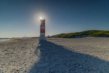The lighthouse with sunflair sunflare, glare from behind against brilliant blue sky at Helgoland...