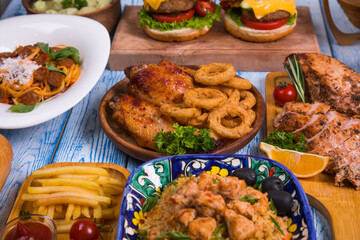 Wooden table full of delicious grilled bbq and fried food. Meat and vegetables. Summer picnic background. Delicious dinner.