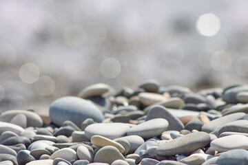 Pebble stones on sea shore natural background soft focus. Beach pebbles with defocused lights bokeh.