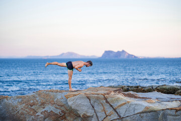 Hombre haciendo yoga en la playa