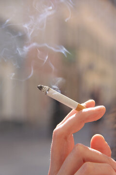Eine Hand hält eine rauchende Zigarette