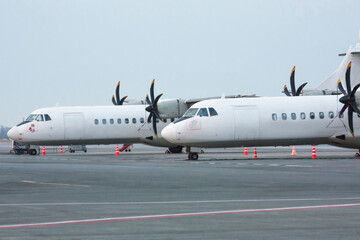 Two white passenger turboprop aircrafts on the airport apron