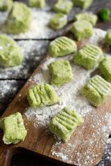 Italian cuisine. Preparation of potato gnocchi with parmesan cheese. Healthy food on a brown wooden background. Basil gnocchi macro. The process of preparing the dough