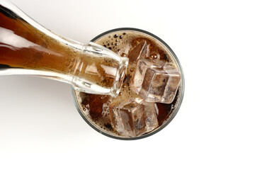 Vertiendo bebida refrescante de cola en un vaso con hielos, visto desde arriba