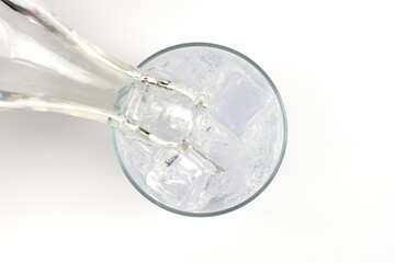 Vertiendo bebida refrescante de tónica en un vaso con hielos, visto desde arriba