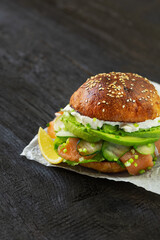Burger with salmon, avocado, cucumber and cream cheese. Whole wheat bun. Healthy food concept