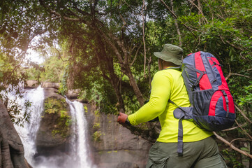Naklejka na ściany i meble Tourists carry backpack, hiking nature trail, traveling ecotourism. Tourist trekking to see amazing beauty of Haew Suwat Waterfall. Unseen Khao Yai National Park, Thailand, UNESCO World Heritage Area.