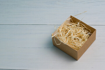 Craft gift box with light wood filler on wooden background with copy space