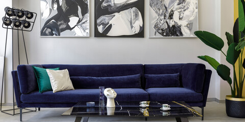 Stylish and modern living room interior with blue velvet sofa, mock up paintings, design black...