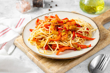 Pasta with eggplant, sweet pepper and carrots in a plate on a light gray table. Traditional Italian dish with vegetables close-up
