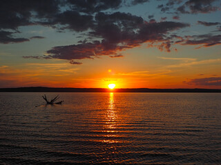 Summer sunset on the Kama river. Driftwood in the water. Beautiful clouds. Russia, Ural, Perm...