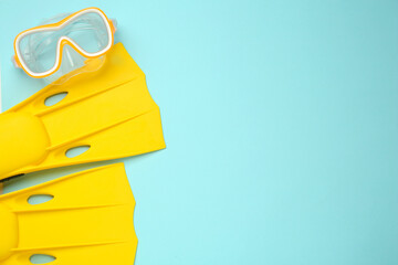 Pair of yellow flippers and diving mask on turquoise background, flat lay