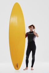 Surfer near surfboard and show thumb up gesture