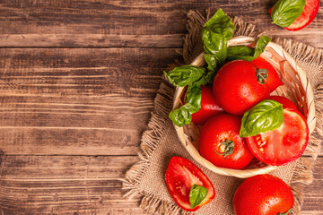 Ripe red tomatoes with fresh basil in a wicker basket