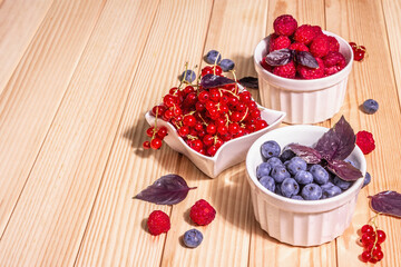Assorted ripe berries in bowls. Fresh raspberries, blueberries, and red currants