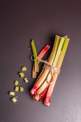Fresh rhubarb stalks and cut pieces on a black stone background