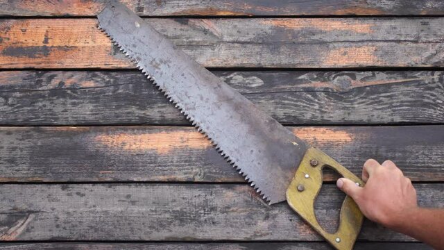 Close up view 4k stock video footage of old used vintage tools. Man puts old rusty saw and axe on weathered wooden surface background