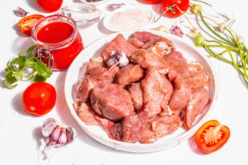 Raw pork pieces, tomatoes, spices, and herbs