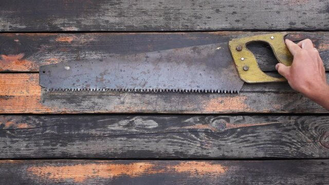 Close-up top view flatlay 4k stock video footage of old used vintage tools. Man puts old rusty saw and axe on weathered wooden surface background