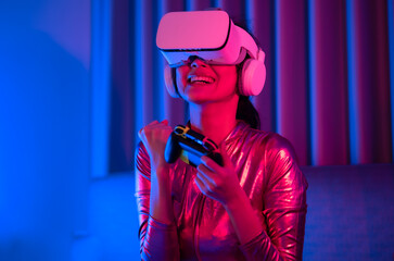 Young asian woman is using virtual reality headset. Neon light studio portrait. Concept of virtual reality, simulation, gaming and future technology.Asian woman play game in bedroom.