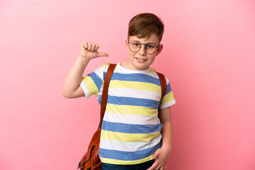Little redhead caucasian boy isolated on pink background proud and self-satisfied