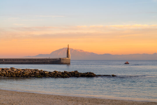 View of Punta del Santo with a boat from a Tarifa Port breakwater, the Morocco Mountains across the Straits of Gibraltar in the distance