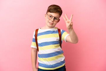 Little redhead caucasian boy isolated on pink background happy and counting three with fingers