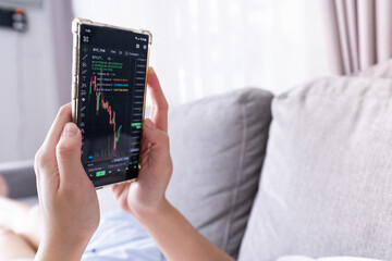 Close up hand holding smart phone with stock market of cryptocurrency digital charts rate dynamic, trading data indexes growth.