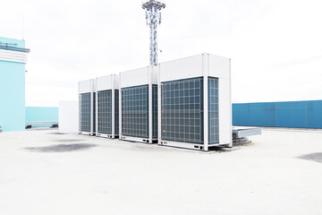 Fototapeta na wymiar Big air conditioner compressor source heat pumps on the wall outdoor on the roof top of the building. It is used in large industrial buildings for cooling. with sky and spotlights in the background