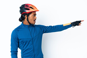 Young cyclist man with braids over isolated background pointing away