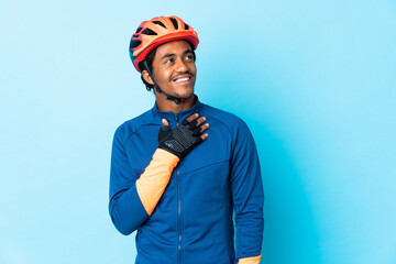 Young cyclist man with braids over isolated background looking up while smiling