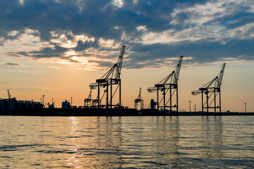 Obraz premium Cranes and industrial equipment in the sea, cargo port. View from the sea.