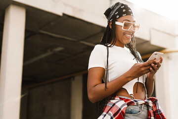 Black young woman smiling while using mobile phone