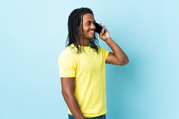 Delivery African American man with braids isolated on white background keeping a conversation with the mobile phone
