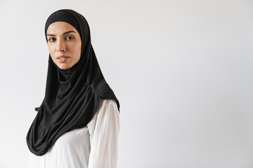 A portrait of the muslim woman in hijab looking at the camera in the white studio