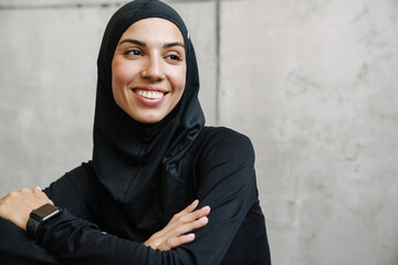 Young muslim woman in hijab smiling and looking aside indoors