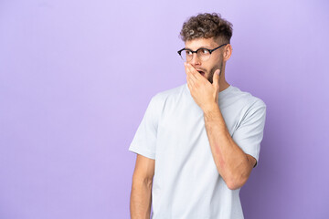 Delivery caucasian man isolated on purple background doing surprise gesture while looking to the side