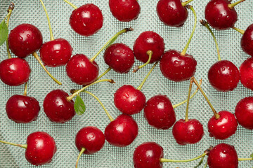 washed cherries with water drops on a steel sieve grid. abstract food background.