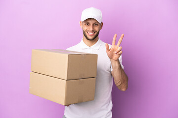 Delivery caucasian man isolated on purple background happy and counting three with fingers