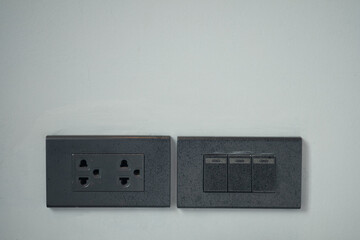 Black colour light switch and outlet plug on the wall at home.