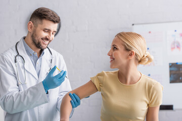 positive doctor in latex gloves vaccinating happy woman in clinic