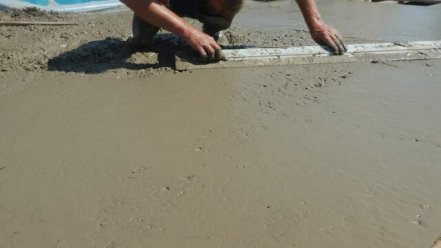 The builder levels the liquid concrete, makes a flat blind area