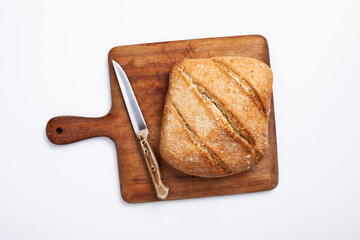 freshly baked bread on wooden cutting board isolated on white background, top view
