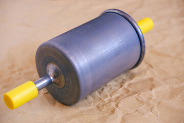 Auto parts. Car fuel gasoline filter. Close-up photo of the filter on craft paper.