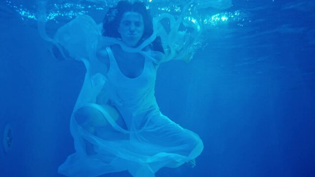 Young woman in white dress swimming , diving under the water . Woman swimming . Underwater shot . Shot on RED EPIC Cinema Camera in slow motion.